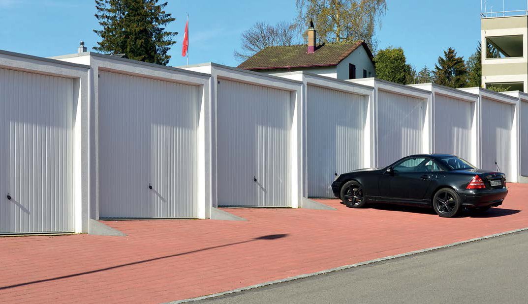 Voiture noire garée devant des garages en batterie